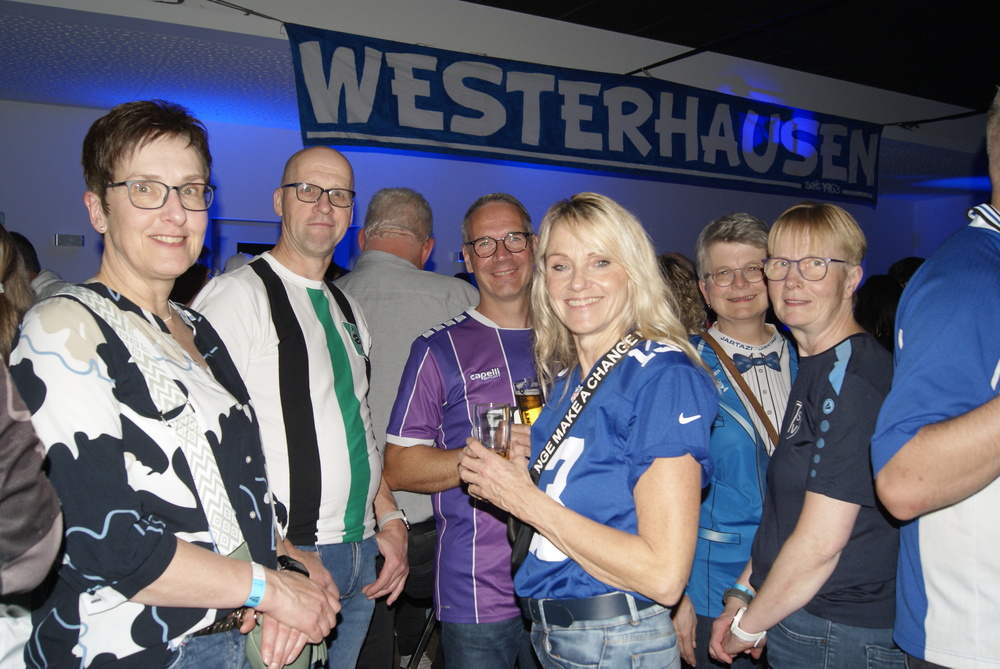 Gruppe von Menschen in Freizeitkleidung steht vor einem Banner mit der Aufschrift 'WESTERHAUSEN'.