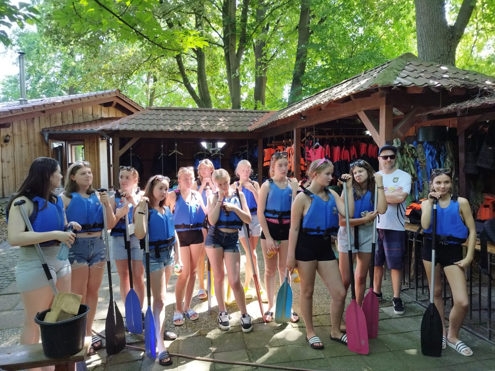 Abschluss Volleyball U16 am 21.06.2026 Gruppe von Jugendlichen mit Schwimmwesten und Paddeln steht vor Holzhütten im Wald