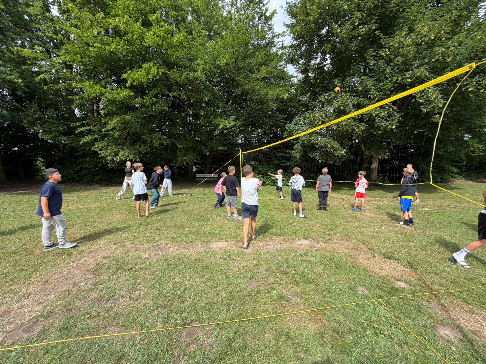 Zeltlager Meesdorf 2026 - Tag 3 - Volleyball Gruppe von Kindern spielt Volleyball auf einer Wiese vor Bäumen